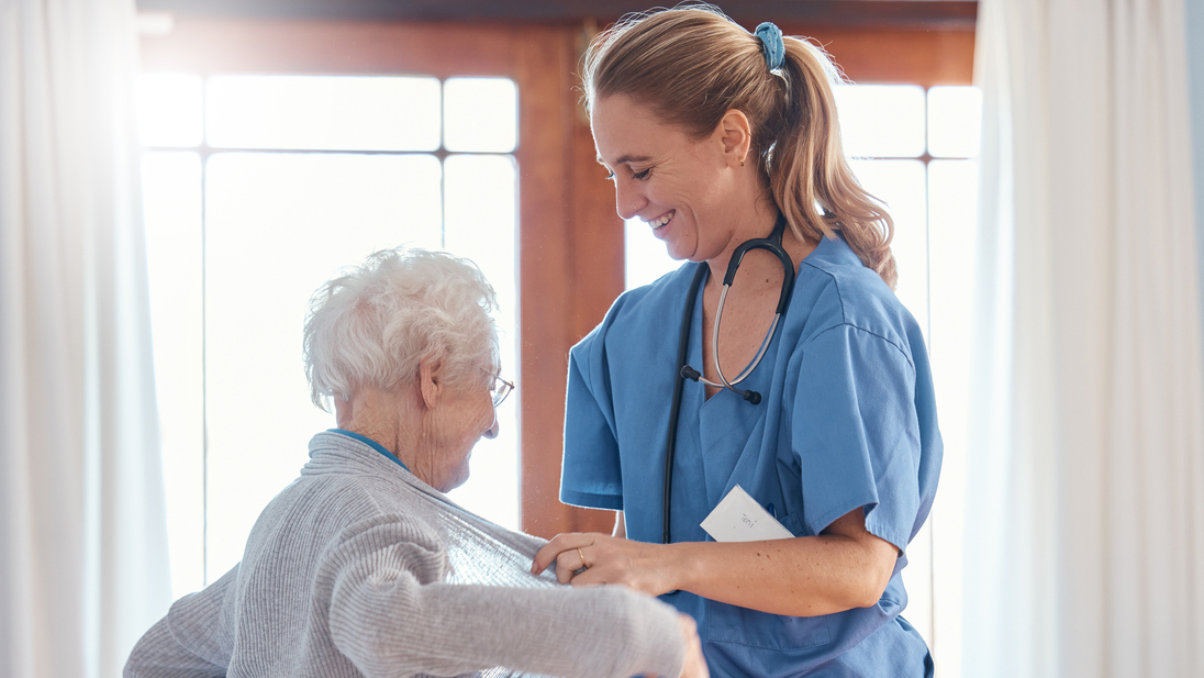 Nurse helps senior woman in nursing home with her sweater.jpg