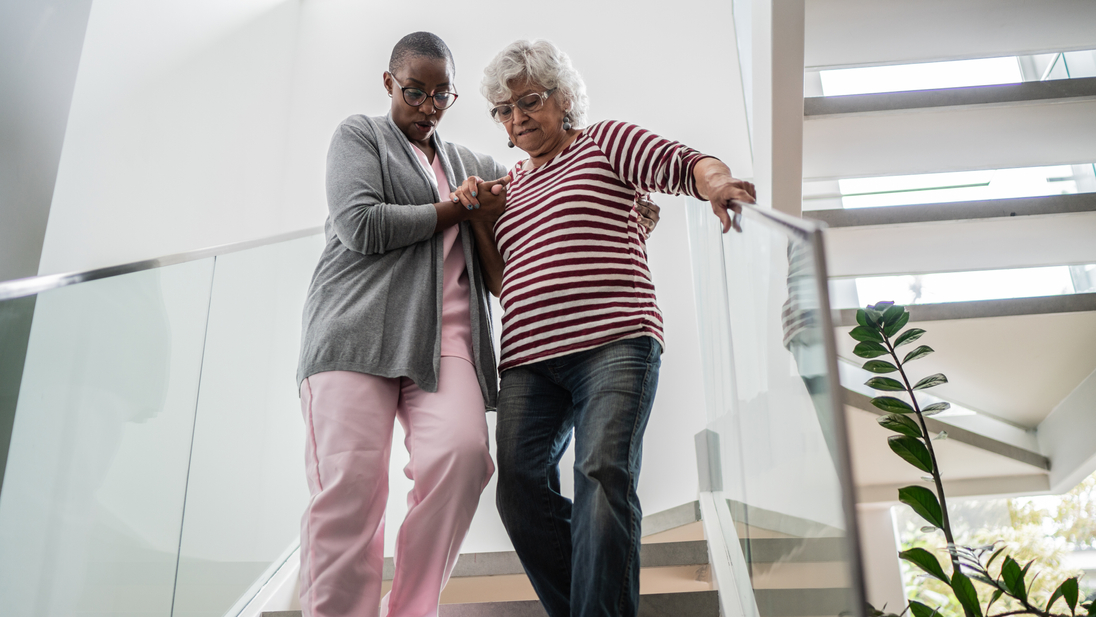 Nurse helping a senior woman walking down stairs.jpg